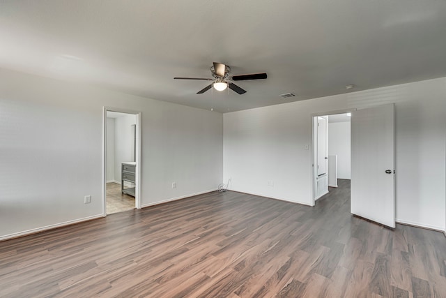 unfurnished bedroom featuring visible vents, baseboards, dark wood finished floors, ensuite bathroom, and a ceiling fan