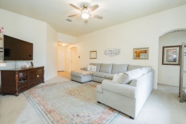 carpeted living room with a ceiling fan, arched walkways, visible vents, and baseboards