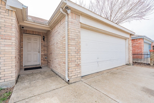 exterior space with concrete driveway, brick siding, fence, and an attached garage