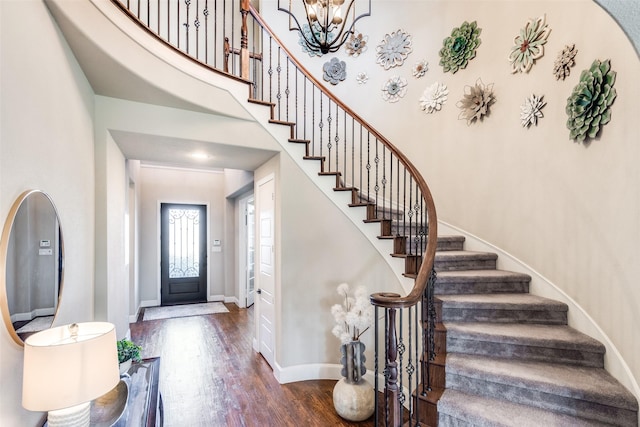 entrance foyer with baseboards, a notable chandelier, a high ceiling, and wood finished floors