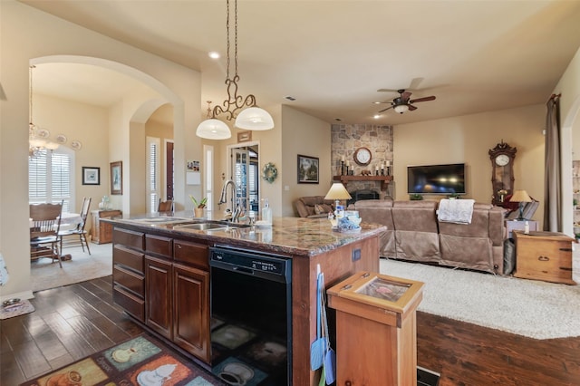 kitchen with an island with sink, arched walkways, a sink, ceiling fan, and dishwasher