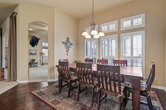 dining space with a chandelier, arched walkways, baseboards, and hardwood / wood-style flooring