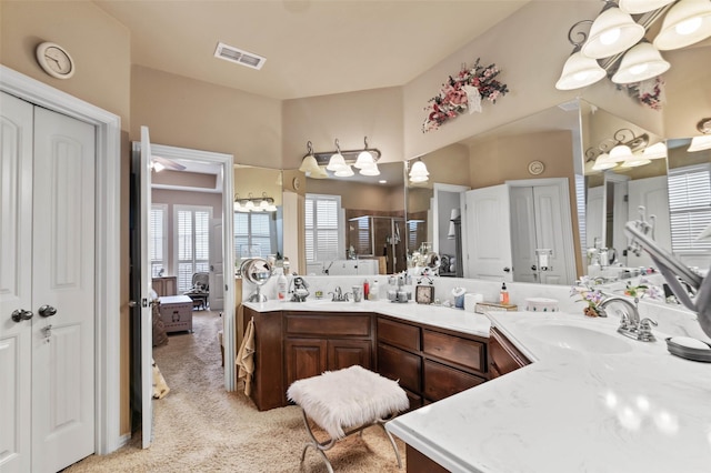 bathroom featuring visible vents, a shower stall, a chandelier, double vanity, and a sink