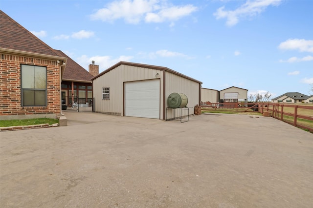 detached garage featuring driveway and fence