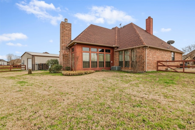 rear view of house with a shingled roof, a lawn, fence, and a chimney