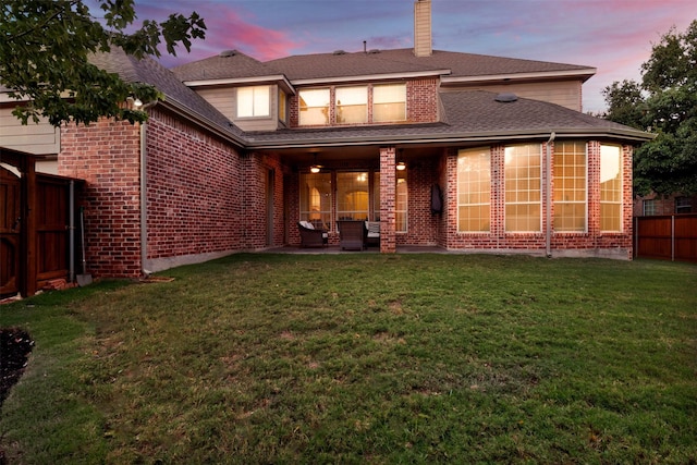 rear view of house with brick siding, a patio, a chimney, a lawn, and fence private yard