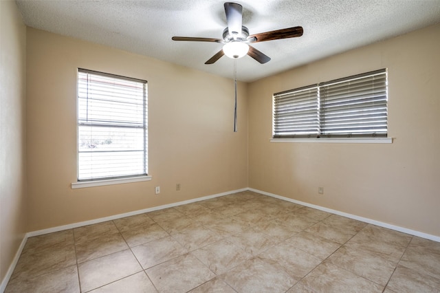 tiled spare room featuring baseboards, a textured ceiling, and ceiling fan