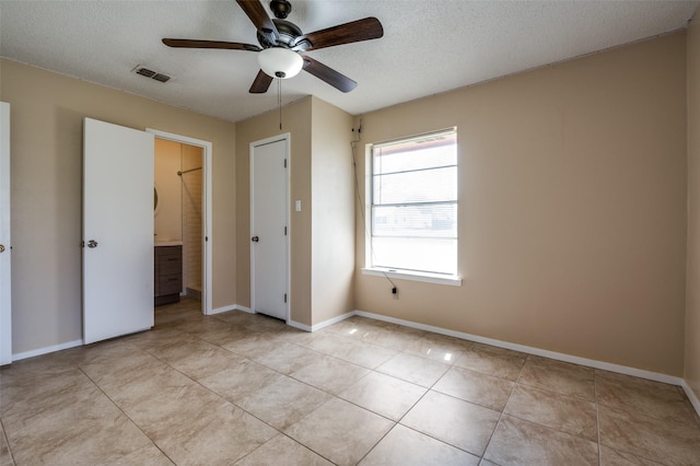 unfurnished bedroom with visible vents, baseboards, light tile patterned floors, a textured ceiling, and a ceiling fan
