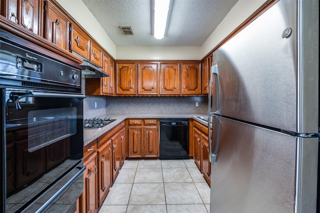 kitchen featuring brown cabinets, black appliances, tasteful backsplash, a textured ceiling, and light tile patterned flooring