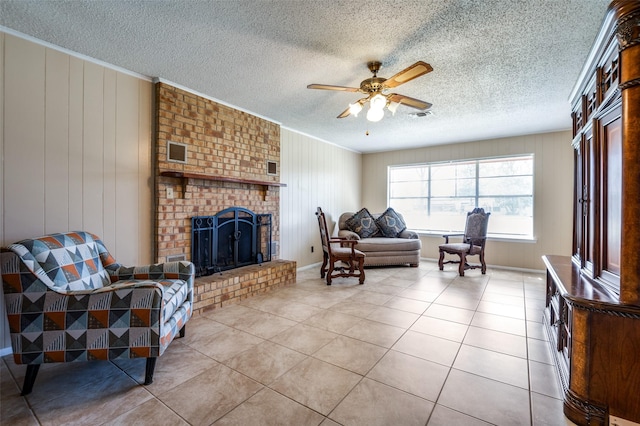 living room with tile patterned flooring, visible vents, ceiling fan, a fireplace, and a textured ceiling