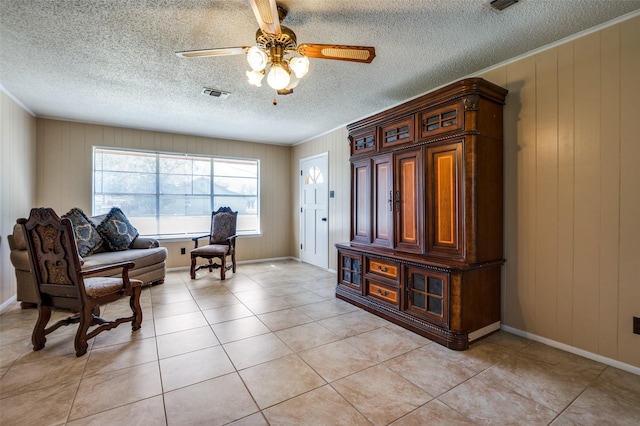 foyer featuring visible vents, a ceiling fan, a textured ceiling, light tile patterned flooring, and crown molding