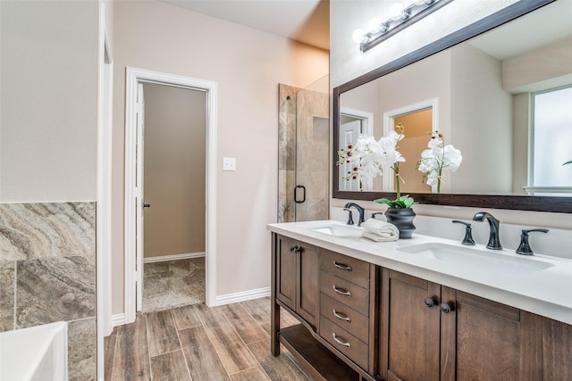 full bathroom with double vanity, a sink, a tile shower, and wood finished floors