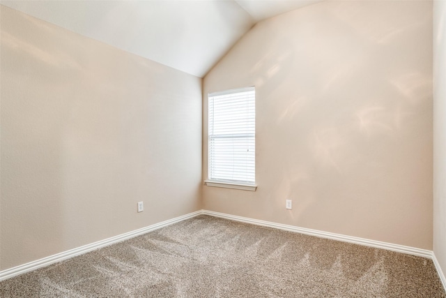 carpeted spare room with vaulted ceiling and baseboards