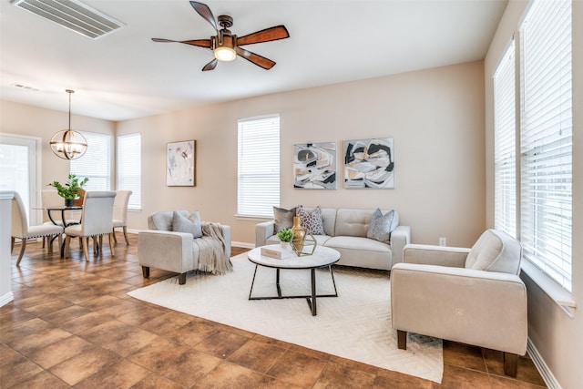 living room featuring visible vents, a wealth of natural light, and ceiling fan with notable chandelier