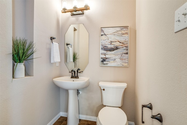 half bath with baseboards, a sink, and toilet