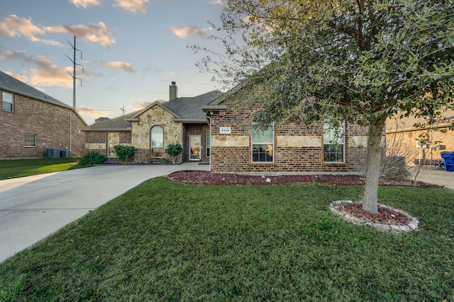 view of front of house featuring driveway, a chimney, central air condition unit, a front yard, and brick siding