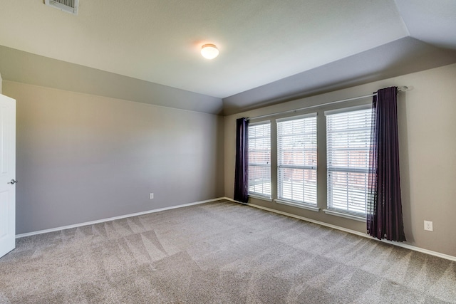 carpeted empty room with lofted ceiling, visible vents, and baseboards