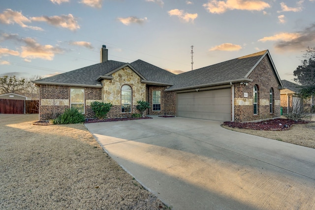 view of front of home featuring driveway, brick siding, a chimney, and an attached garage