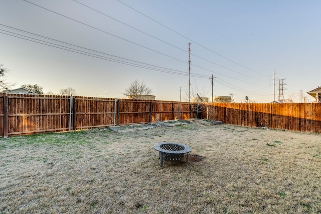 view of yard with a fenced backyard and a fire pit