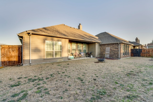 back of house featuring roof with shingles, a patio, a chimney, fence private yard, and a fire pit