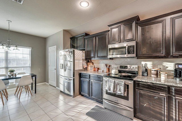 kitchen featuring stainless steel appliances, dark brown cabinetry, decorative backsplash, and light stone countertops