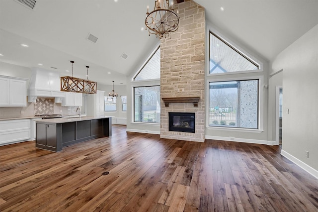 unfurnished living room with a fireplace, dark wood finished floors, a wealth of natural light, and a notable chandelier