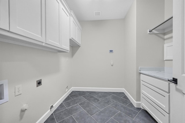 laundry area featuring cabinet space, visible vents, baseboards, dark tile patterned flooring, and hookup for an electric dryer