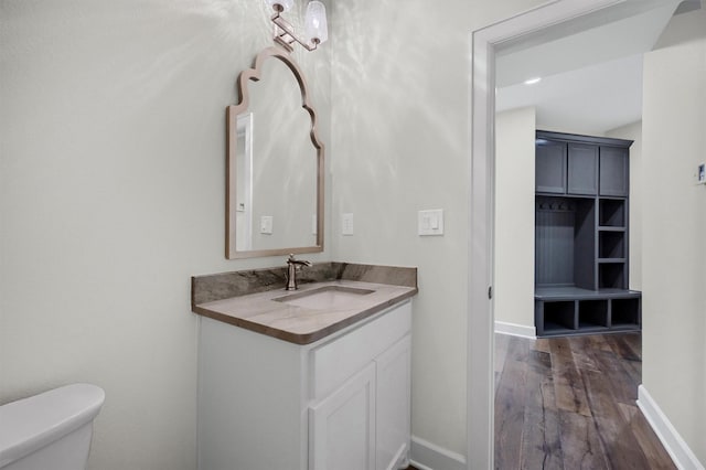 bathroom featuring vanity, wood finished floors, toilet, and baseboards