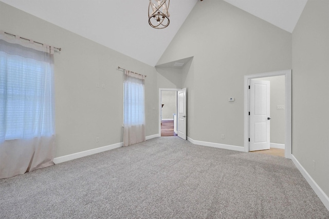 unfurnished bedroom with high vaulted ceiling, carpet flooring, a notable chandelier, and baseboards