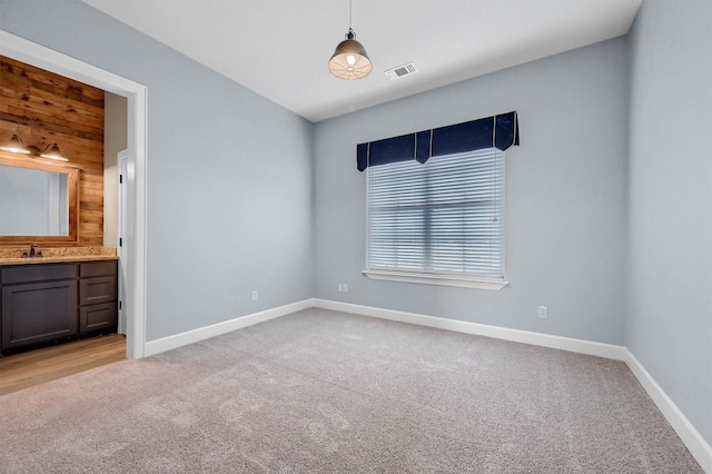 unfurnished bedroom with light carpet, ensuite bath, visible vents, and baseboards