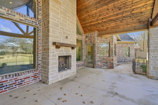 view of patio with fence and an outdoor stone fireplace