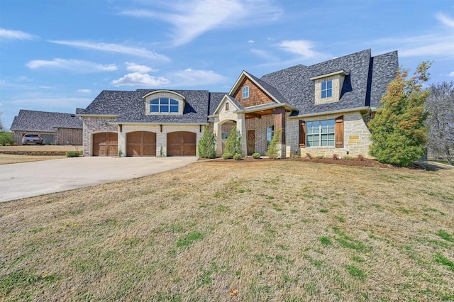 french country inspired facade with stone siding, a shingled roof, concrete driveway, and a front yard