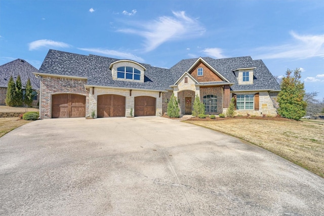 french provincial home with stone siding, a shingled roof, concrete driveway, and a front yard