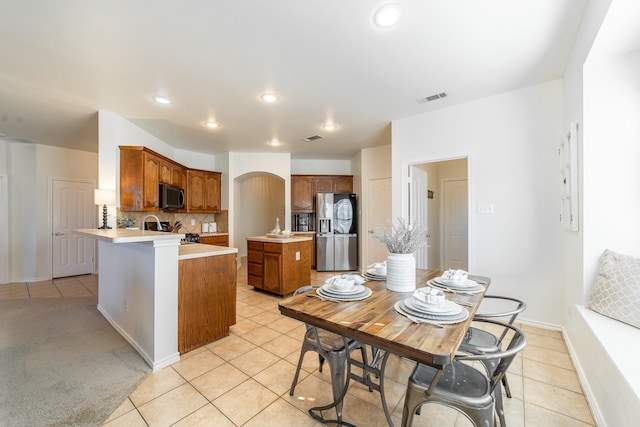 kitchen with a peninsula, visible vents, light countertops, appliances with stainless steel finishes, and backsplash