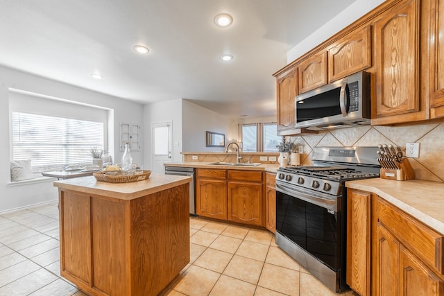 kitchen featuring stainless steel appliances, light countertops, backsplash, light tile patterned flooring, and a peninsula