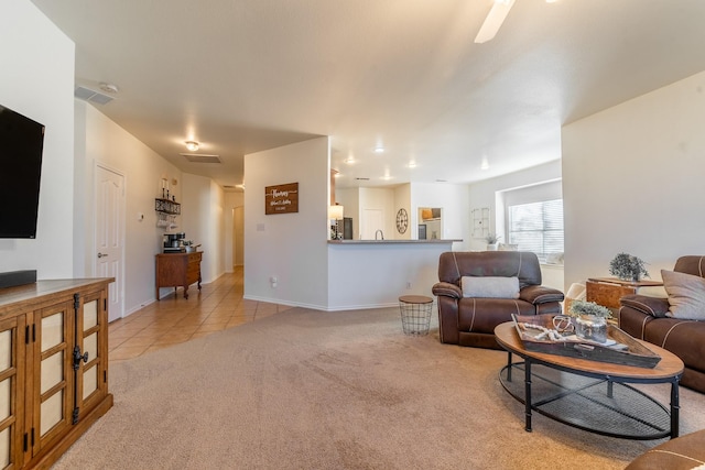 living area featuring light colored carpet, visible vents, baseboards, and light tile patterned flooring