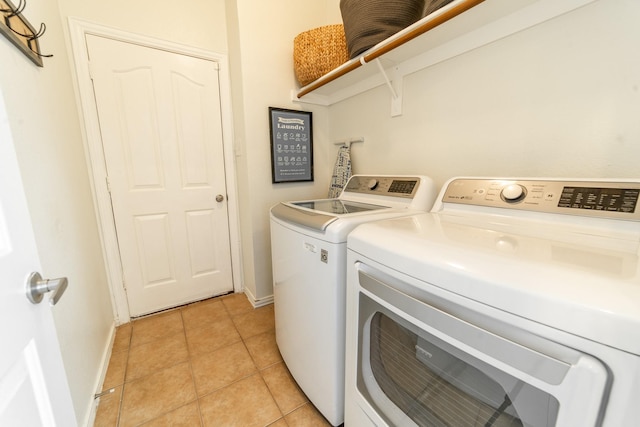 laundry area featuring light tile patterned floors, laundry area, washer and clothes dryer, and baseboards