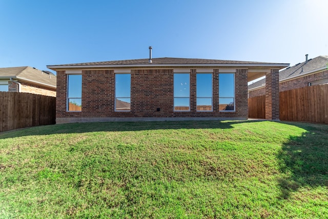 back of property with a yard, brick siding, and a fenced backyard