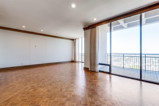 empty room featuring floor to ceiling windows, baseboards, crown molding, and recessed lighting