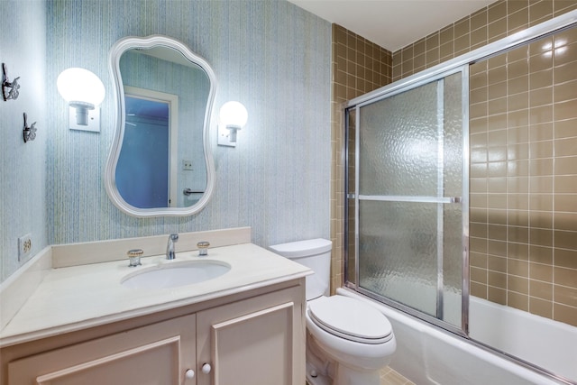 bathroom with toilet, wallpapered walls, enclosed tub / shower combo, and vanity