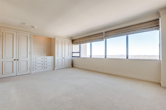 unfurnished bedroom with multiple closets, light colored carpet, and baseboards