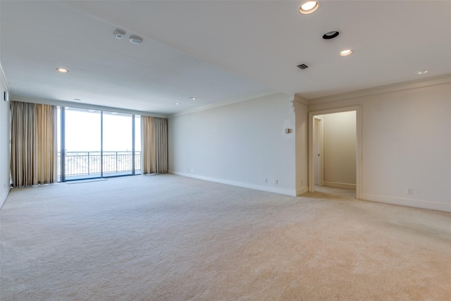 empty room with baseboards, visible vents, light colored carpet, and crown molding