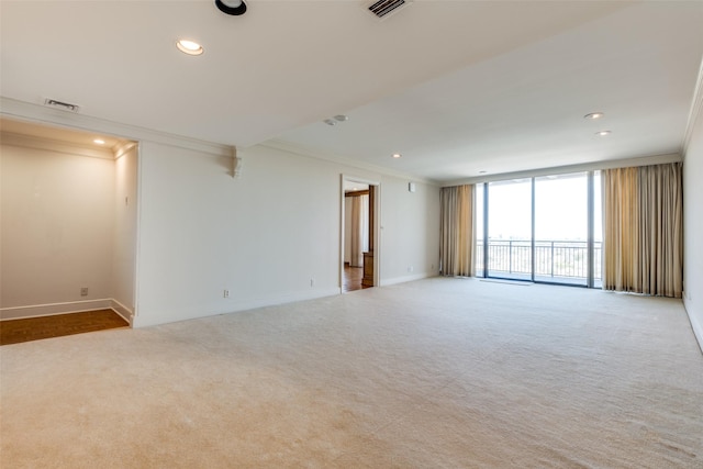 empty room featuring visible vents, ornamental molding, carpet, a wall of windows, and recessed lighting