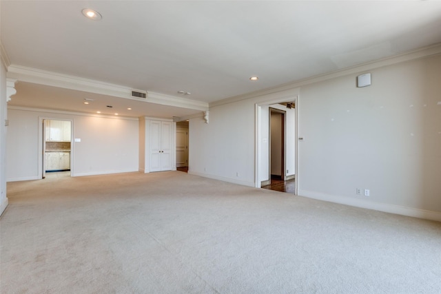 carpeted spare room with visible vents, crown molding, and baseboards