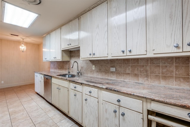 kitchen with light tile patterned floors, backsplash, stainless steel dishwasher, a sink, and baseboards