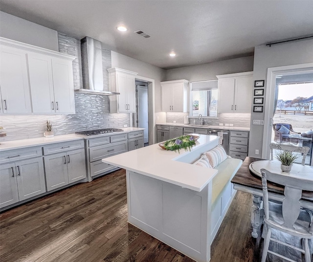 kitchen featuring beverage cooler, dark wood finished floors, a sink, wall chimney exhaust hood, and a center island