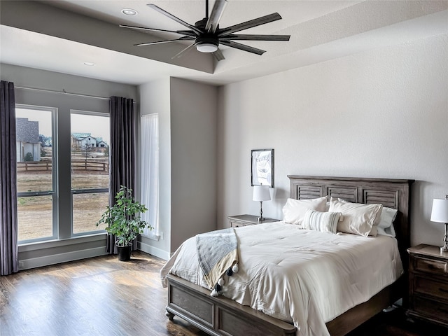 bedroom with a ceiling fan, wood finished floors, and baseboards