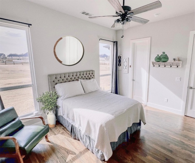 bedroom featuring ceiling fan, wood finished floors, visible vents, and baseboards