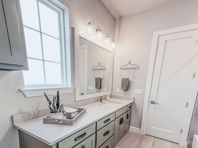 bathroom with vanity, wood finished floors, and baseboards