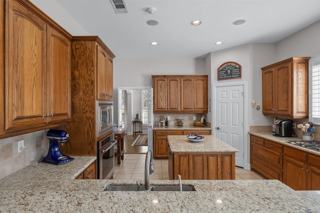 kitchen featuring light tile patterned floors, visible vents, light stone counters, stainless steel appliances, and a sink